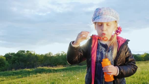 Funny girl in cap blowing bubbles - Кадри, відео