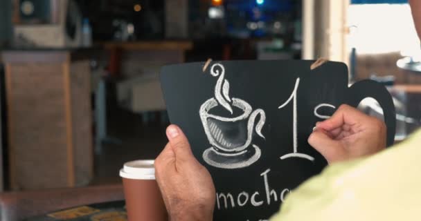 Homem escrevendo preço do café no quadro de giz
 - Filmagem, Vídeo