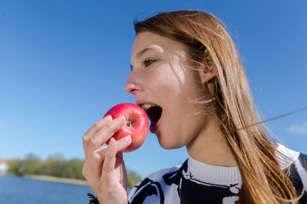junge Frau beißt genüsslich in einen roten Apfel - Foto, Bild