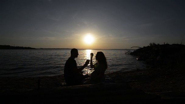 Una coppia che aspetta un bambino seduto sulla riva del fiume. Felice gravidanza coppia
 - Filmati, video