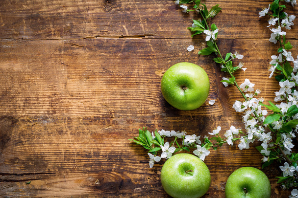 Wooden background with green apples and cherry blossoms - Fotografie, Obrázek