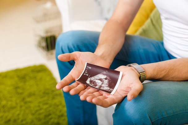 Der zukünftige Vater hält das Ultraschallbild in der Hand - Foto, Bild