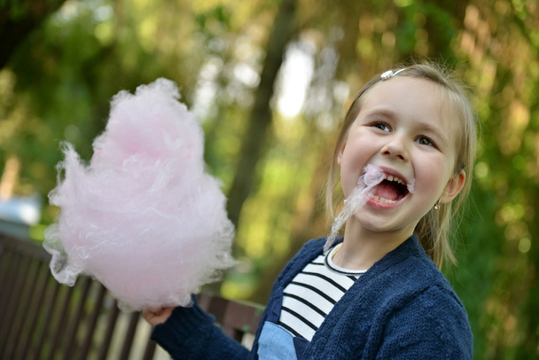 Adorable petite fille mangeant des bonbons-fil dentaire à l'extérieur en été - Photo, image