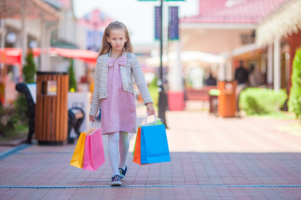 Adorabile bambina con borse della spesa che cammina in città all'aperto
 - Foto, immagini