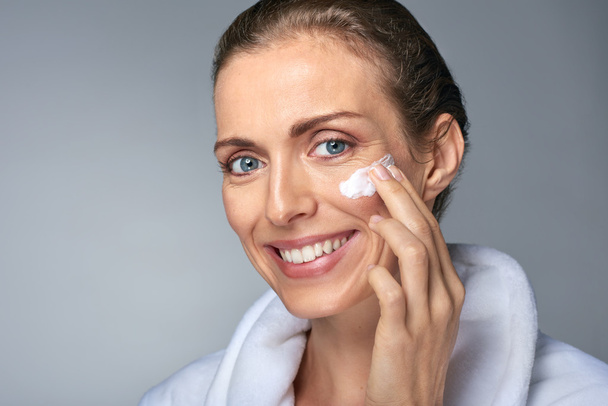 Middle age woman applying face moisturiser - Фото, зображення