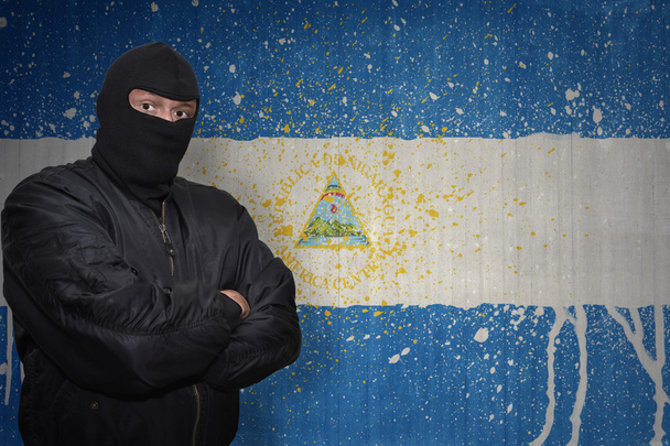 homem perigoso em uma máscara que está perto de uma parede com a bandeira nacional pintada de nicarágua
 - Foto, Imagem