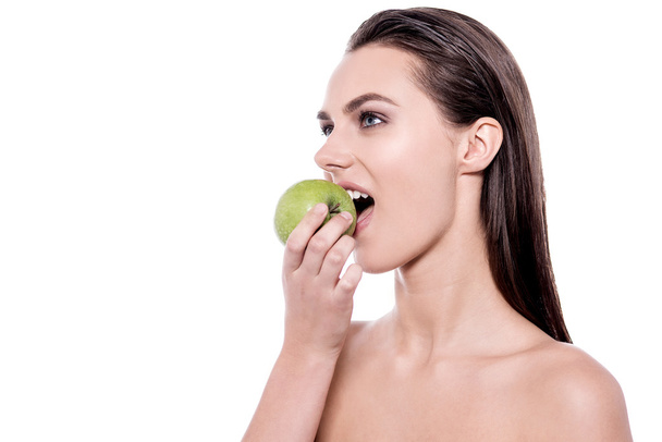Young woman eating a green apple - Фото, зображення