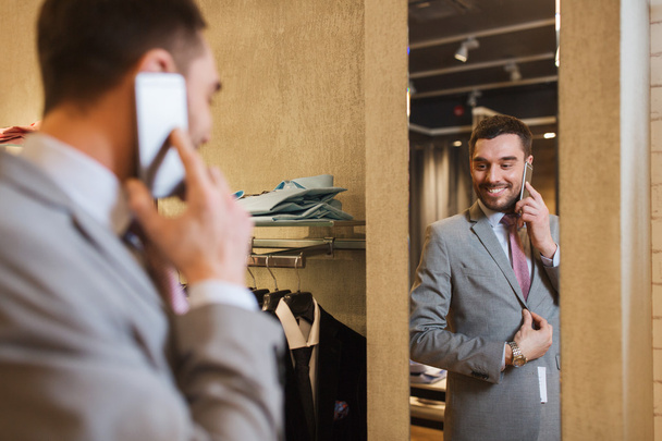 man calling on smartphone at clothing store mirror - Photo, Image