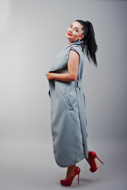 Full length studio shot of brunette girl at gray coat, advertise - Valokuva, kuva
