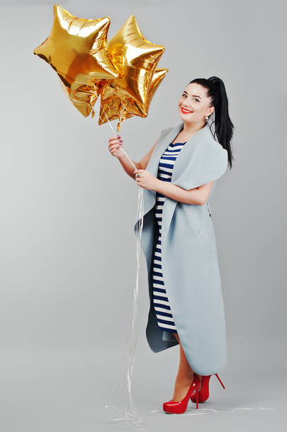 Young smiled woman with gold balloons at hands background gray i - Photo, image