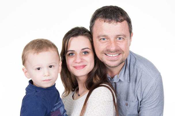 Boldog fiatal család szép gyermek pózol fehér háttér - Fotó, kép