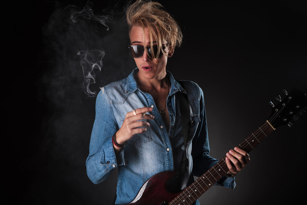 sorprendido joven guitarrista fumar cigarrillo
 - Foto, Imagen
