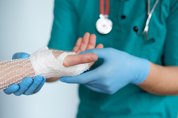 Nahaufnahme eines Arztes, der nach einem Unfall eine Hand bandagiert - Foto, Bild