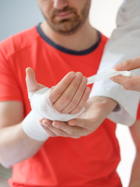 γιατρός επίδεση το χέρι ενός άνδρα άθλημα μετά από ατύχημα - Φωτογραφία, εικόνα