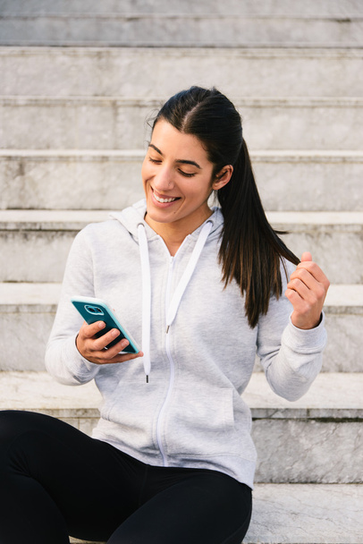 Sporty young woman texting on smartphone - Photo, image