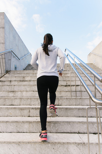 Спортивна жінка біжить і скелелазіння сходами вид ззаду
 - Фото, зображення