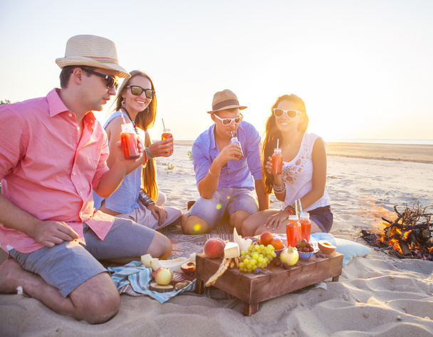 Φίλους συνεδρίαση στην άμμο στην παραλία και πίνοντας λεμονάδα - Φωτογραφία, εικόνα