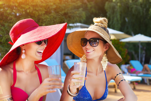 Mulheres bebendo um coquetel enquanto relaxam na piscina
 - Foto, Imagem