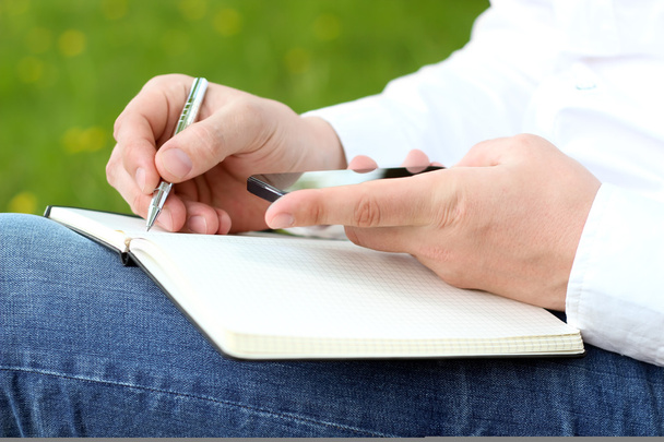 Egy ember használ mozgatható szúró telefon és toll írásban közelről - Fotó, kép