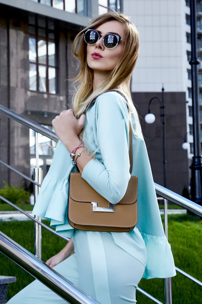 Fashion beautiful sexy woman blonde hair wear stylish trend clothes costume organic materials sunglasses luxury life style brand accessory lather bag outdoor of modern building summer time model  - Photo, image