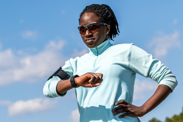 Αφρικανική γυναίκα αξιολόγηση αποτελεσμάτων στο έξυπνο ρολόι. - Φωτογραφία, εικόνα