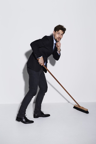 Businessman sweeping up with finger on lips - Foto, immagini