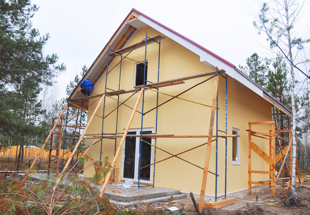 Hausneubau außen. Bauunternehmer montieren Dichtungen und Fassaden mit Dachkonstruktion - Foto, Bild
