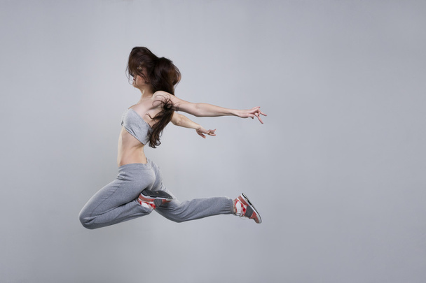 Beautiful young woman dancer jumping in studio - Foto, afbeelding