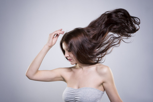 Beautiful young woman with flowing hair in studio - Фото, зображення