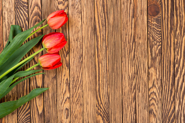 Red tulips on a wooden background. Space for text. Top view - Foto, Imagen