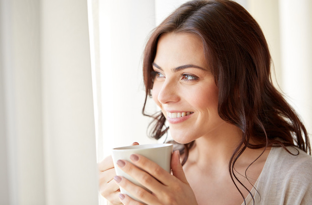 happy woman with cup of tea or coffee at home - Fotoğraf, Görsel