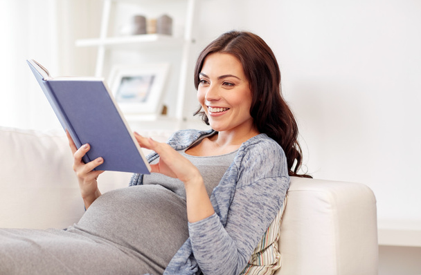 happy pregnant woman reading book at home - Foto, imagen