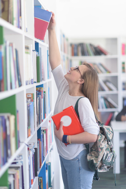 female student selecting book to read in library - Photo, Image