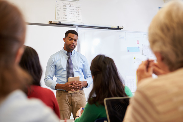 Male teacher listening to students at class - Фото, зображення