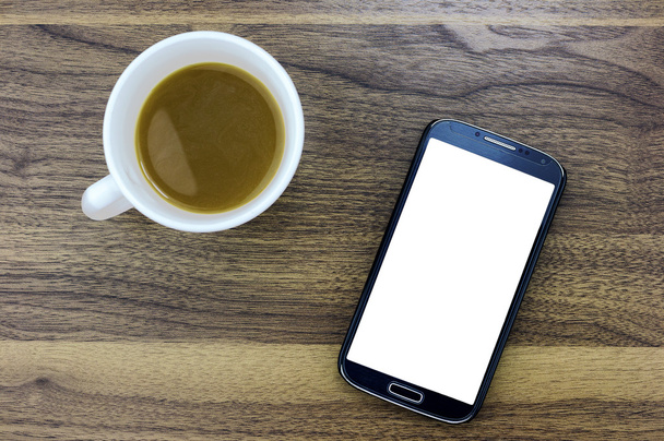 Slimme telefoon met leeg scherm zitten naast een kopje koffie  - Foto, afbeelding