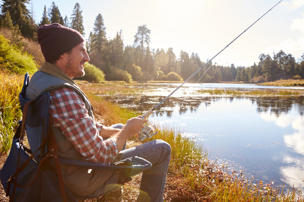 Man relaxing and fishing by lakeside - Photo, image