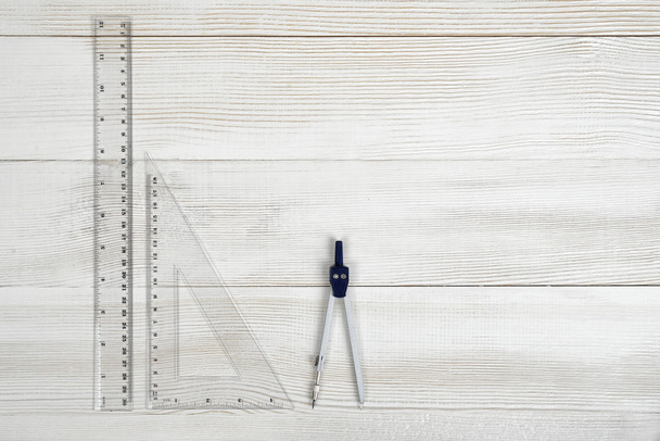 Flat lay of riangle centimeter rulers and engineering divider on wooden surface. - Foto, Imagen