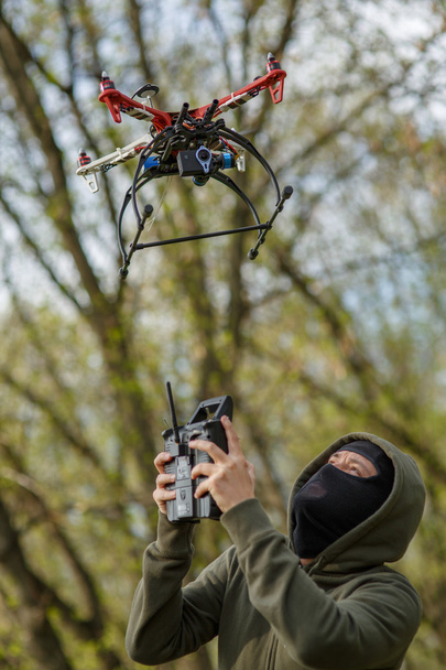 Man in mask operating a drone with remote control. - Fotografie, Obrázek