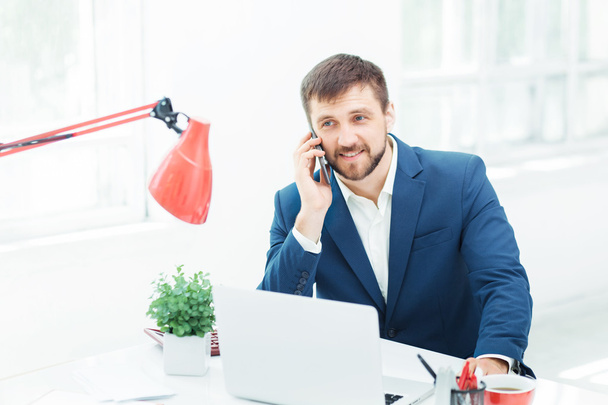 Portrait of businessman talking on phone in office - Фото, изображение