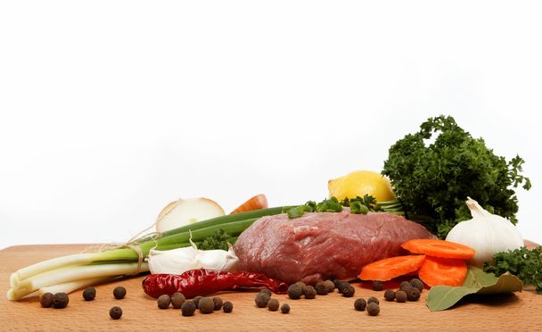 Carne cruda, verduras y especias aisladas sobre una mesa de madera
. - Foto, Imagen