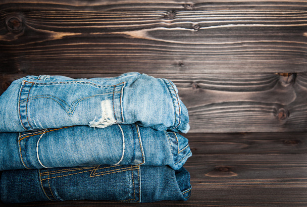 Jeans gestapelt auf einem hölzernen Hintergrund - Foto, Bild