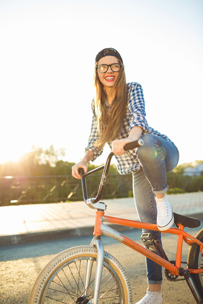 Lovely young woman in a hat riding a bicycle on city background  - Фото, зображення