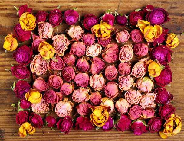 Fleurs roses rouges et jaunes séchées sur une vieille table en bois
 - Photo, image
