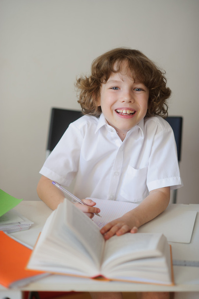 Мальчик делает домашнее задание сидя за школьным столом
 - Фото, изображение