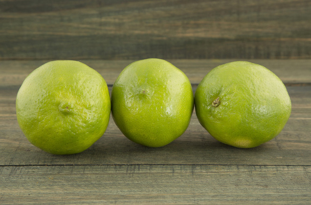 Green lemons on wooden table - Foto, immagini