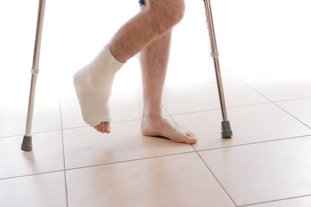 Νεαρός άνδρας με ένα σπασμένο αστράγαλο και ένα πόδι χυτό - Φωτογραφία, εικόνα