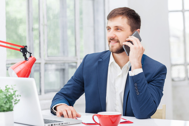 Portrait of businessman talking on phone in office - Photo, Image