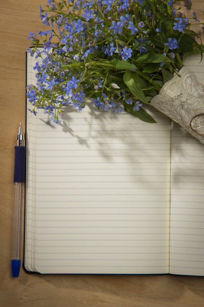 A bouquet of flowers forget-me, notebook and pen on the wooden t - Foto, Imagen