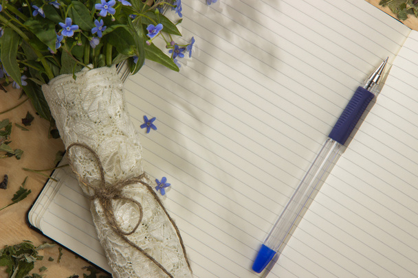 ein Strauß Blumen vergissmeinnicht, Notizbuch und Stift auf dem hölzernen T - Foto, Bild