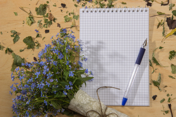 A bouquet of flowers forget-me, notebook and pen on the wooden t - Foto, Bild